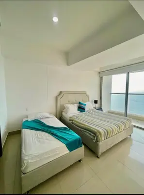 two beds in a bedroom with a large window at 1PE-AL Apartamento de 1 alcoba frente al mar con Aire acondicionado, Piscina y Wifi in Cartagena de Indias