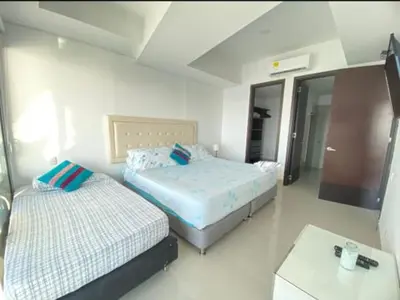 a bedroom with two beds and a table and a tv at 1PE-AL Apartamento de 1 alcoba frente al mar con Aire acondicionado, Piscina y Wifi in Cartagena de Indias