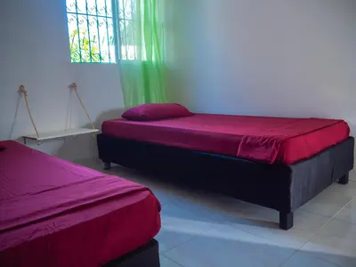 two beds in a room with a window at Lovely and close to airport, sea, and old town in Cartagena de Indias