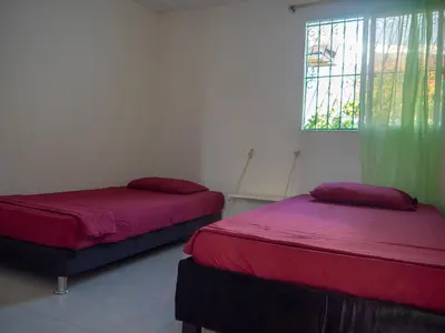 two beds in a room with a window at Lovely and close to airport, sea, and old town in Cartagena de Indias
