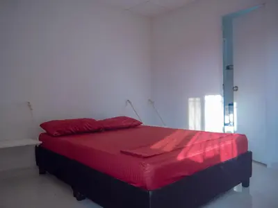a bed in a room with a red blanket on it at Lovely and close to airport, sea, and old town in Cartagena de Indias