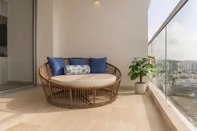 a wicker chair with blue pillows on a balcony at Suite Familiar Vista al Mar, Day Bed WiFi CB1315 in Cartagena de Indias