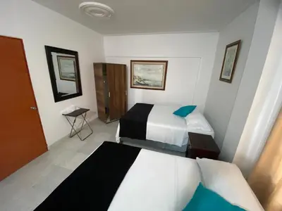 a hotel room with two beds and a table at Paraíso en Bocagrande habitaciones in Cartagena de Indias