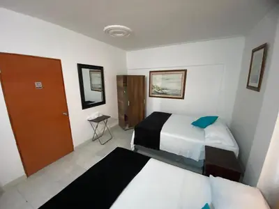 a hotel room with two beds and a door at Paraíso en Bocagrande habitaciones in Cartagena de Indias