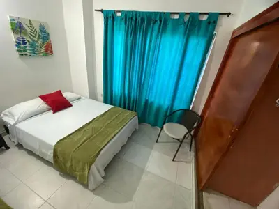 a bedroom with a bed and a blue curtain at Paraíso en Bocagrande habitaciones in Cartagena de Indias