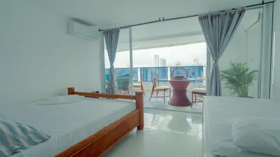 a bedroom with two beds and a balcony at Hermoso Pent-House Piso 21 con vista privilegiada in Cartagena de Indias