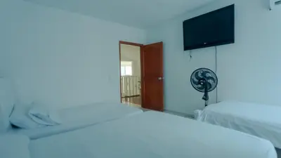 a bedroom with a white bed and a fan at Hermoso Pent-House Piso 21 con vista privilegiada in Cartagena de Indias