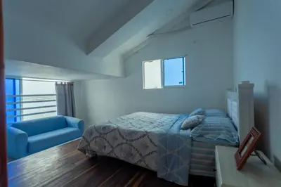 a bedroom with a bed and a blue couch at Hermoso Pent-House Piso 21 con vista privilegiada in Cartagena de Indias