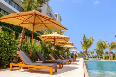 a row of lounge chairs with umbrellas next to a pool at Apartamento Morros C28 acceso directo al Mar Manzanillo in Cartagena de Indias