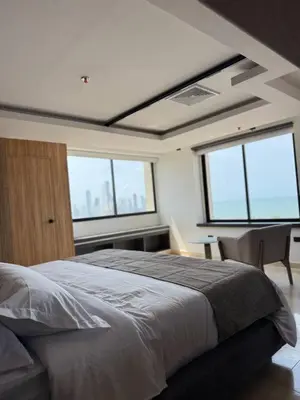 a bedroom with a bed and a table and windows at Del Mar City View in Cartagena de Indias