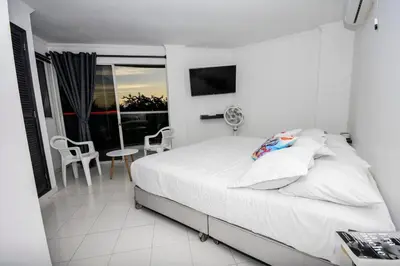 a white bedroom with a bed and a table and chairs at Frontbeach Apartment Cartagena HighSpeed internet in Cartagena de Indias