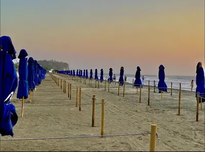 a row of blue umbrellas and chairs on a beach at Hermoso Apartamento Cartagena Salida directa al Mar in Cartagena de Indias
