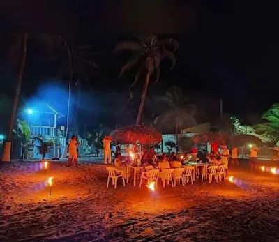 a group of people sitting at tables on the beach at night at Cabañas Kosta Azul in San Bernardo del Viento