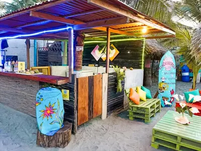 a restaurant on the beach with surfboards and a bar at Cabañas Kosta Azul in San Bernardo del Viento