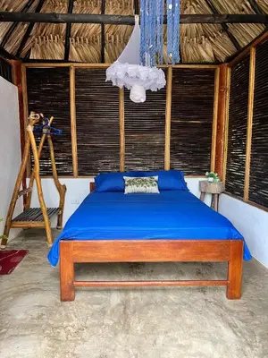a bedroom with a bed with blue sheets and a tripod at Hospedaje VILLA CRETA in Isla Fuerte