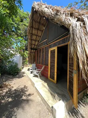 a thatch roofed building with a bench sitting outside at Hospedaje VILLA CRETA in Isla Fuerte