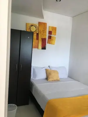 a bedroom with a bed with a cabinet and paintings on the wall at Valmar apartamentos in Cartagena de Indias
