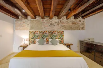 a bedroom with a large bed with a brick wall at Bololá Hotel in Cartagena de Indias