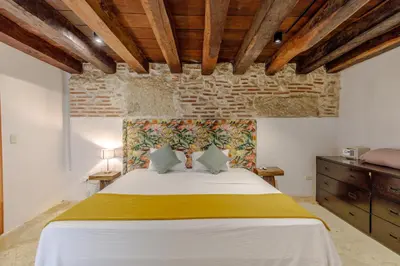 a bedroom with a large bed with a stone wall at Bololá Hotel in Cartagena de Indias