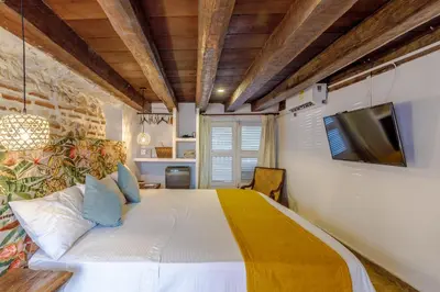 a bedroom with a bed with a tv on the wall at Bololá Hotel in Cartagena de Indias