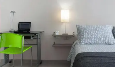 a bedroom with a bed and a desk and a green chair at Golden House Apartments - 2 Bedrooms in Barranquilla