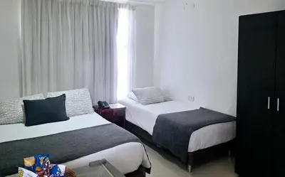 a hotel room with two beds and a window at Golden House Studio Deluxe in Barranquilla