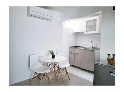 a kitchen with a white table and white chairs at Golden House Studio Deluxe in Barranquilla