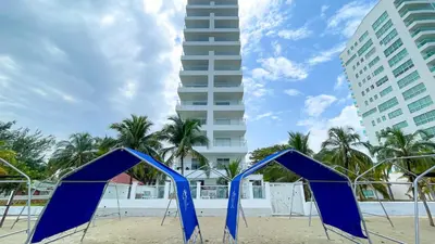 two blue chairs on a beach with a tall building at Magico Apartamento Frente al Mar 3 Habitaciones TV52 in Coveñas