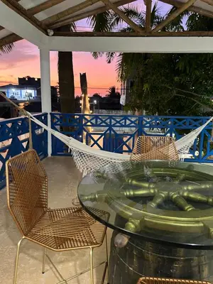 a glass table with chairs and a hammock on a patio at Cuatro Palmas Beach House in Cartagena de Indias