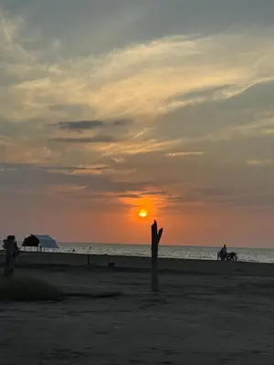 a sunset on the beach with a person with their arms in the air at Apartamentos el mochilero frente a la playa piso 2 apto 4 in Cartagena de Indias