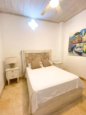 a bedroom with a white bed and a painting on the wall at Casa Beatriz Luxury Colonial House in Cartagena de Indias