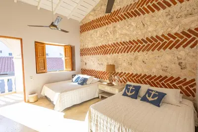 a bedroom with two beds and a stone wall at Casa Beatriz Luxury Colonial House in Cartagena de Indias
