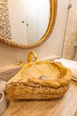 a bathroom with a stone sink and a mirror at Casa Beatriz Luxury Colonial House in Cartagena de Indias
