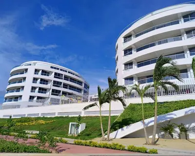 a large white building with palm trees in front of it at Moderno Apartamento en Cartagena in Cartagena de Indias