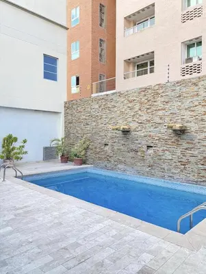 a swimming pool in front of a brick building at Hotel Continental Plaza Barranquilla in Barranquilla