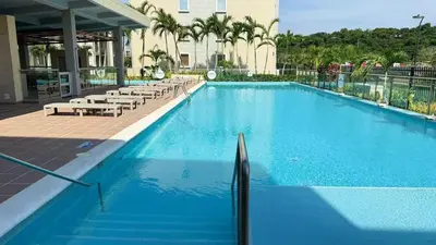 a large blue swimming pool with chairs and a building at Apartamento Cartagena Serena del Mar - Capriella in Manzanillo del Mar
