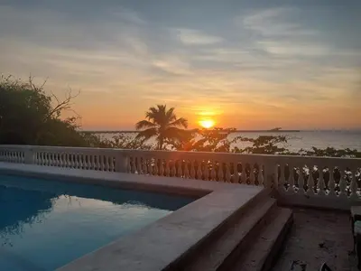 a swimming pool with the sunset in the background at Casa de playa Vistamare in Santa Marta