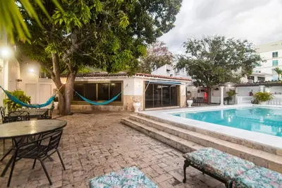 a pool with a table and chairs next to a house at Casa de playa Vistamare in Santa Marta