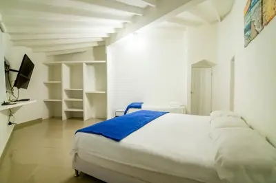 a white bedroom with a bed and a tv at Casa de playa Vistamare in Santa Marta