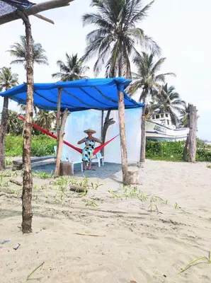 a person sitting on a hammock on a beach at la casablanca moñitos in Moñitos
