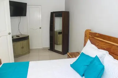 a bedroom with a bed with a wooden headboard and a mirror at Chalet Ledymar in Cartagena de Indias