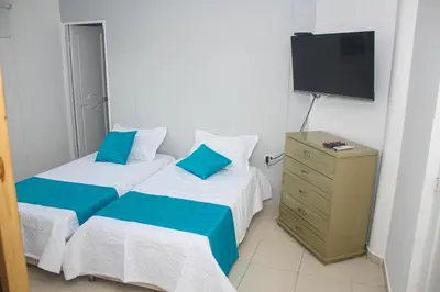 a hotel room with two beds and a television at Chalet Ledymar in Cartagena de Indias