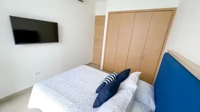 a bedroom with a bed with blue pillows and a tv at Magico Apartamento Frente al Mar 4 Habitaciones BM83 in Coveñas