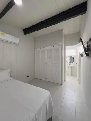 a white bedroom with a bed and a bathroom at Almare Beach House Cartagena in Cartagena de Indias