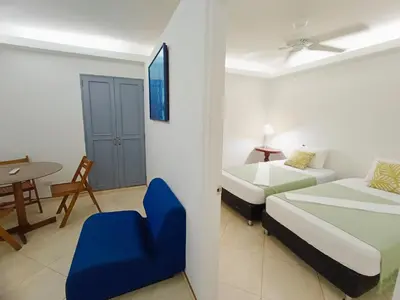 a bedroom with two beds and a blue chair at Acogedores Apartaestudios en Getsemaní in Cartagena de Indias
