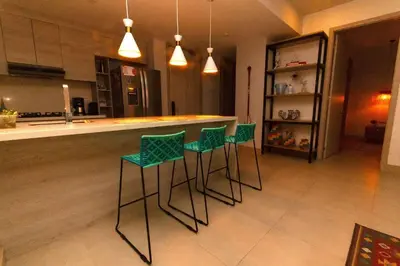 a kitchen with a bar with four green stools at Condominio frente al mar con acceso directo a la playa Morros IO in Cartagena de Indias