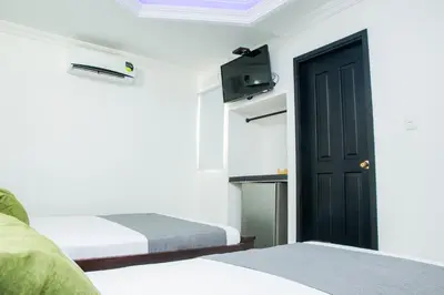 a room with two beds and a door with a tv at Ayenda 1315 Candiac in Barranquilla