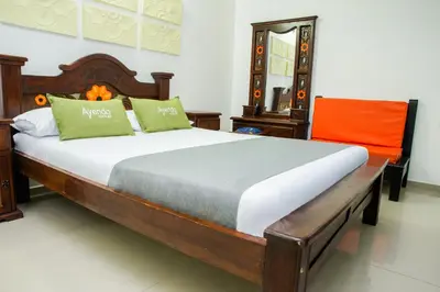 a bedroom with a wooden bed with an orange chair at Ayenda 1315 Candiac in Barranquilla