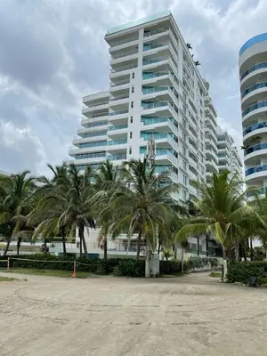 a large white building with palm trees in front of it at Lujoso Penthouse Duplex 403m2 con Terraza Privada y vista al mar in Cartagena de Indias