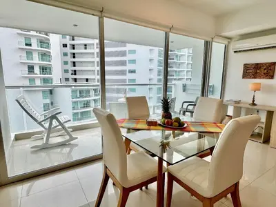 a dining room with a glass table and white chairs at Apartamento 1 dormitorio Morros. Vista Mar y Salida Playa in Cartagena de Indias
